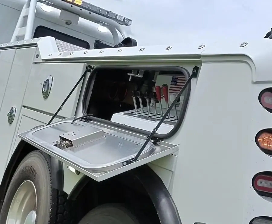 Open tool compartment on the heavy wrecker, rigging gear stowed and ready.